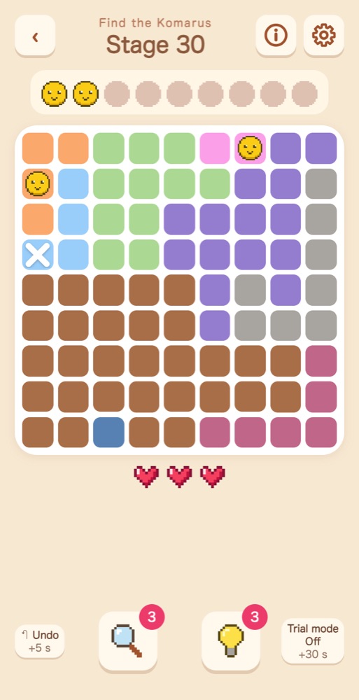 A 9×9 board divided into color regions, with 2 found Komarus and one X marking a cell with no Komaru